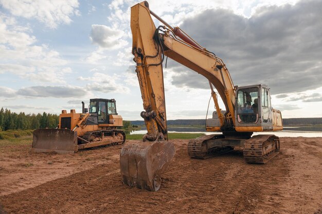 Photo excavator and tractor near the forest lake