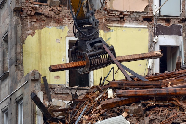 The excavator uses special tongs to dismantle the floors for disassembling the rubble of the floors