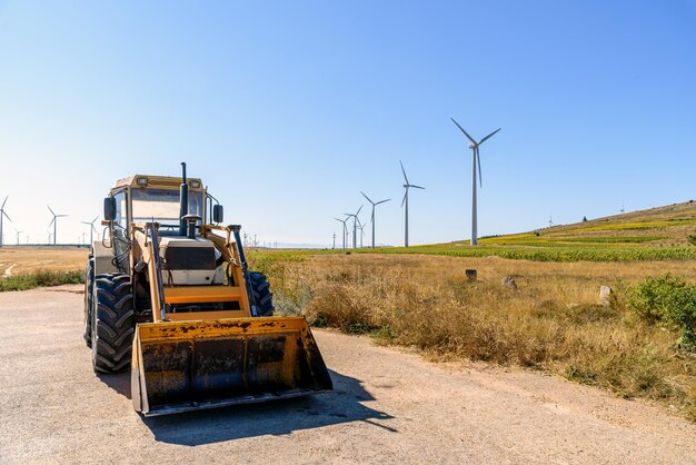 Foto excavator e turbine eoliche sul paesaggio dei terreni agricoli concetti di energia pulita e energie rinnovabili