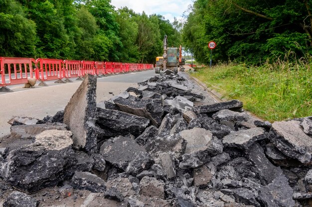 Excavator with hydraulic jack hammer breaking asphalt in preparation for drainage works close up