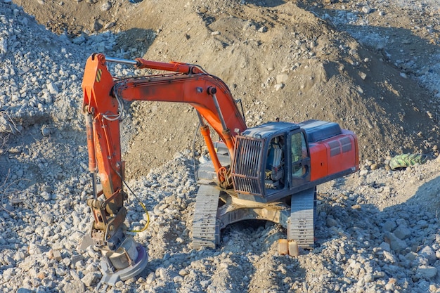 Excavator with a magnetic installation on the boom at the site of the demolition of the building