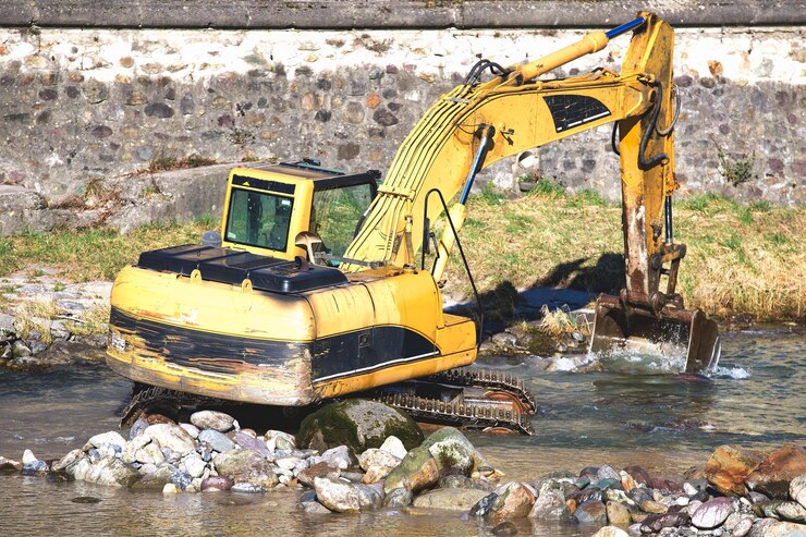 石と水の間の川で働く掘削機