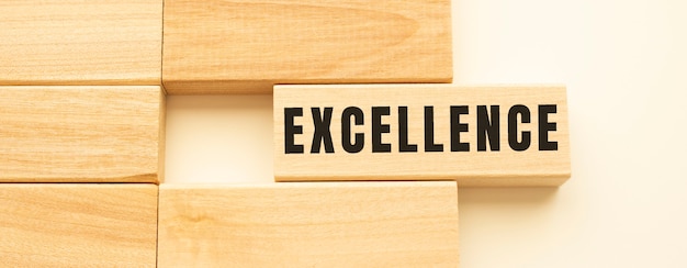 EXCELLENCE text on a strip of wood lying on a white table