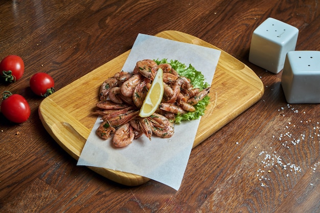 An excellent beer snack is a set of small shrimp fries on parchment on a wooden tray. Pub food. Close up seafood