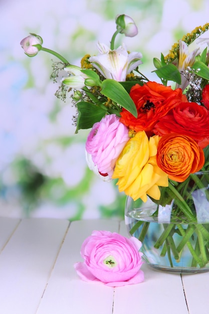 Excellent buttercup flowers in glass vase on wooden table on natural background