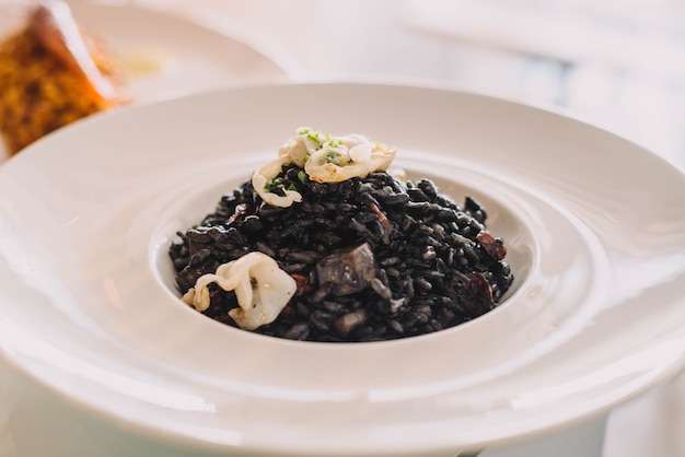 An excellent gourmet dish of seafood paella style squid ink black rice in a fancy restaurant