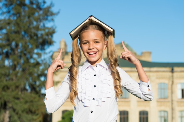 楽しいコンセプトを持つ屋外の教科書で優秀な学生の女の子の勉強