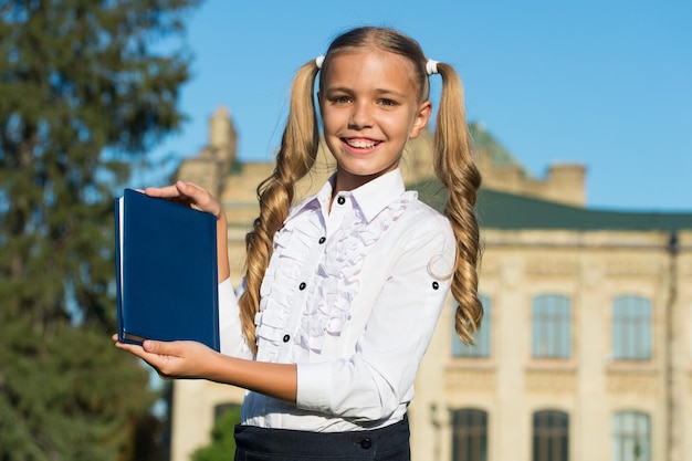 9月のコンセプトの屋外の教科書で優秀な学生の女の子の研究