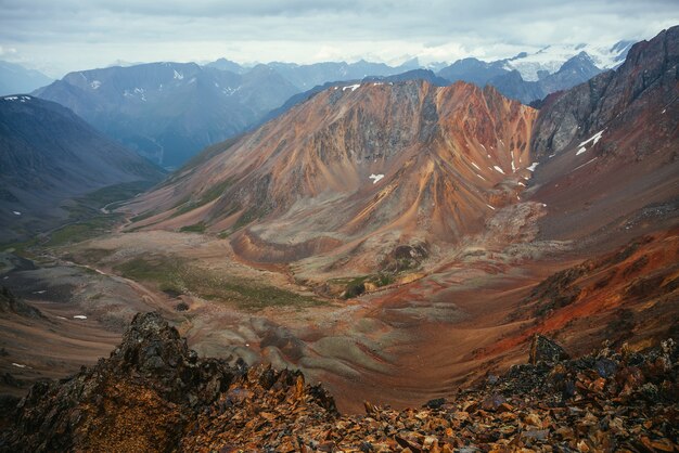 Excellent view from big pointy rocks to motley mountain valley. Scenic mountain landscape with multicolor pointed rocks. Colorful highland scenery with sharp rocks and multicolor mountain valley.