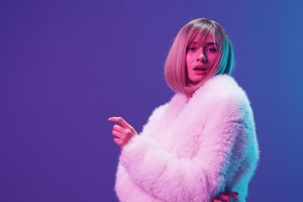 Excited adorable blonde woman in fluffy fur coat sparkly dress\
cross hands open mouth posing isolated in blue violet pink color\
light studio background neon party fashion concept copy space\
banner