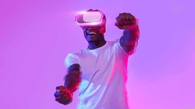 Excited african american guy in VR headset playing online game