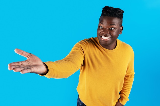 Excited african american man outstretching hand holding invisible object on his palm