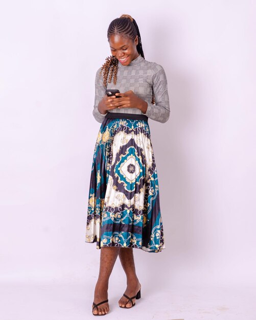 WhiteStudio 배경 빈 공간 위에 서 있는 스마트폰을 사용하여 흥분한 아프리카 소녀