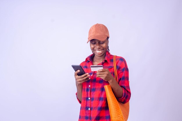Возбужденная африканская дама делает покупки в Интернете со своим мобильным телефоном и кредитной картой