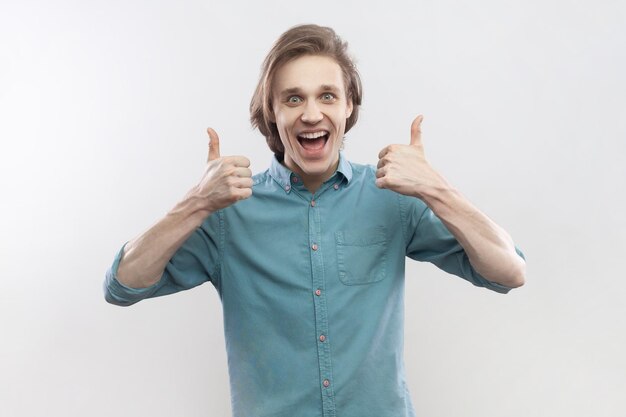 Excited amazed optimistic man showing thumbs up screaming with happiness recommend service