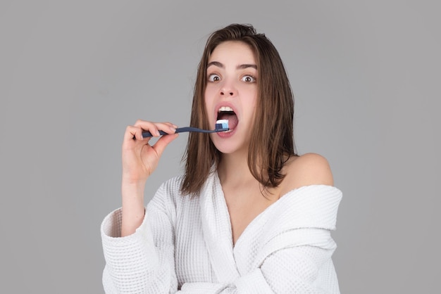 Взволнованная изумленная женщина чистит зубы красивой улыбкой молодой женщины со здоровыми белыми изолированными зубами