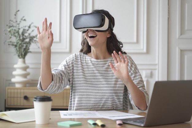 Foto eccitata donna stupita che indossa occhiali vr godendo di un'incredibile esperienza di realtà virtuale al lavoro