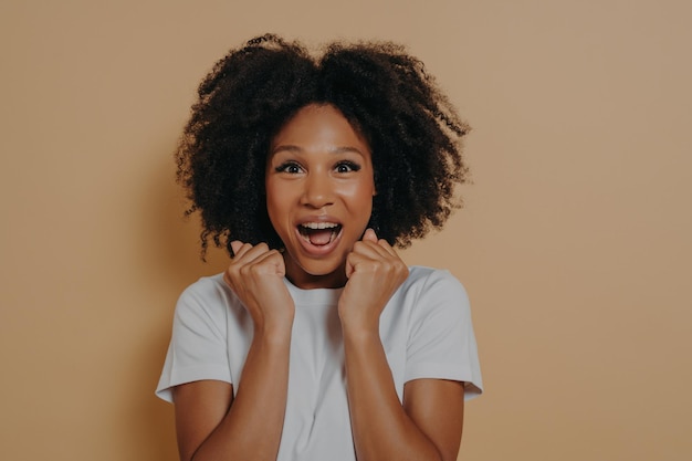 Excited amazed young woman keeping mouth opened and screaming with enjoyement