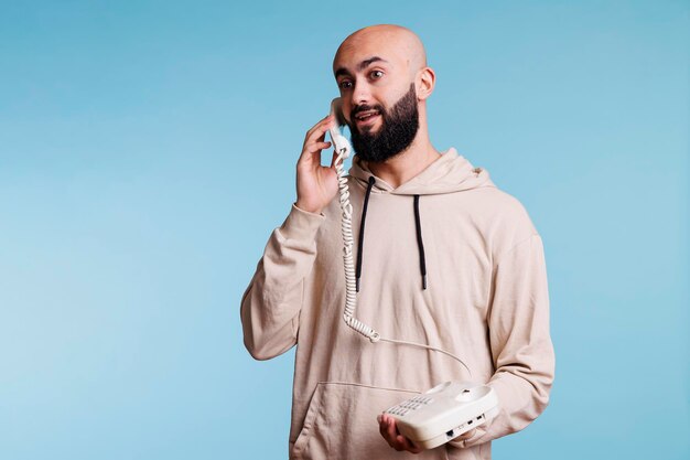 Excited arab man holding landline phone