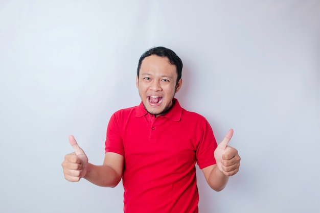 Excited Asian man gives thumbs up hand gesture of approval isolated by white background