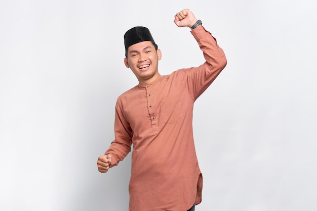 Excited Asian Muslim man celebrating victory isolated over white background