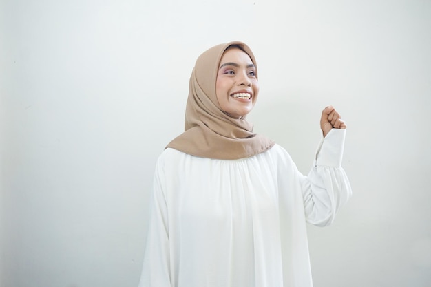 Excited Asian Muslim woman celebrating victory isolated over white background