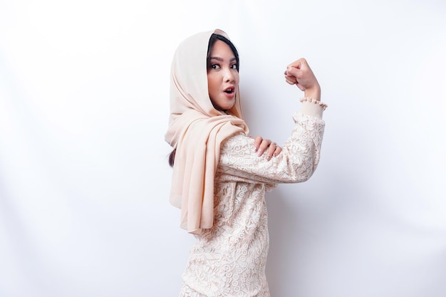 히잡을 쓴 흥분한 아시아 무슬림 여성은 팔과 근육을 자랑스럽게 들어 올려 강한 몸짓을 보였다