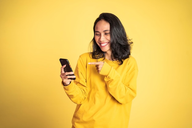 Excited asian woman laugh with finger pointing on her mobile phone