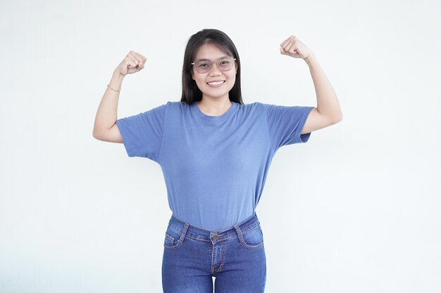 興奮したアジア人女性が誇らしげに腕を上げ大きな笑顔で筋肉を柔らかくします
