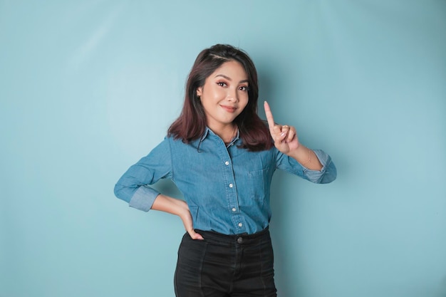 Excited Asian woman wearing a blue shirt giving number 12345 by hand gesture