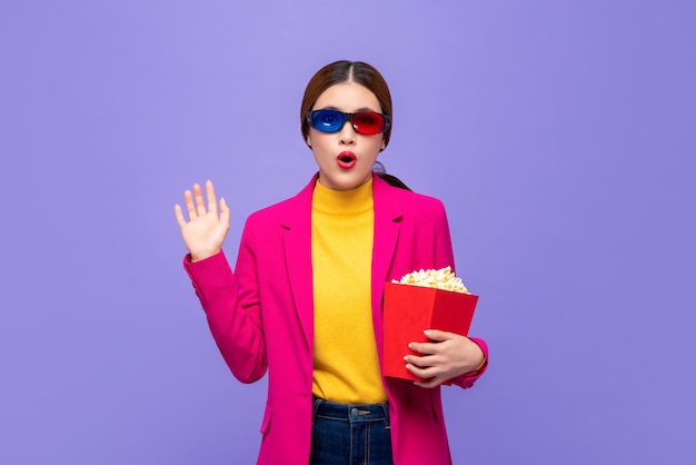 Excited Asian woman with 3D glasses holding popcorn wacthing movie