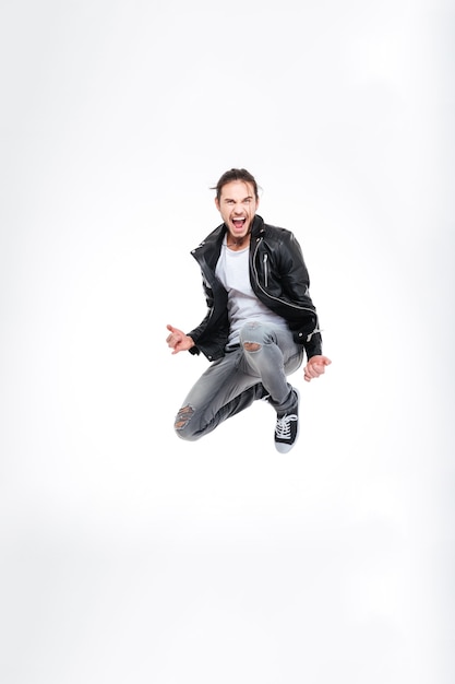 Excited attractive young man screaming and jumping over white background