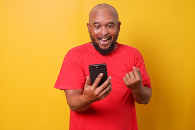 Excited bald bearded man using smartphone winning game getting cashback online gift in mobile app