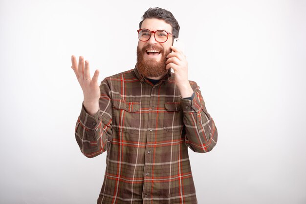 Uomo barbuto emozionante sta parlando al telefono mentre gesticolano.