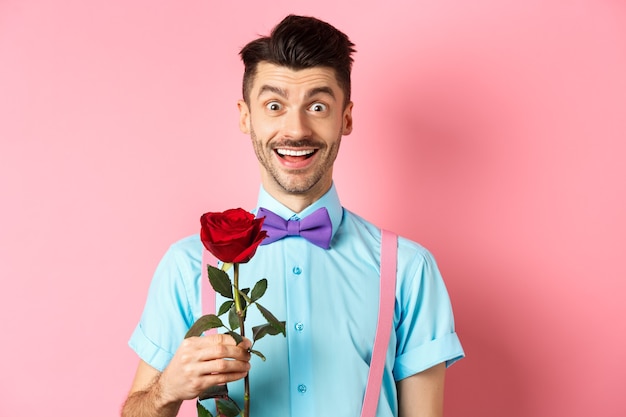 Excited bearded man with moustache and bow-tie waiting for date with red rose