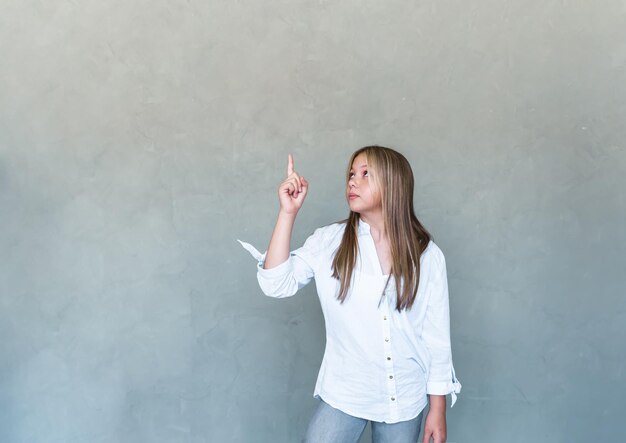 Excited beautiful girl smiling pointing fingers upper left corner and looking pleased at logo