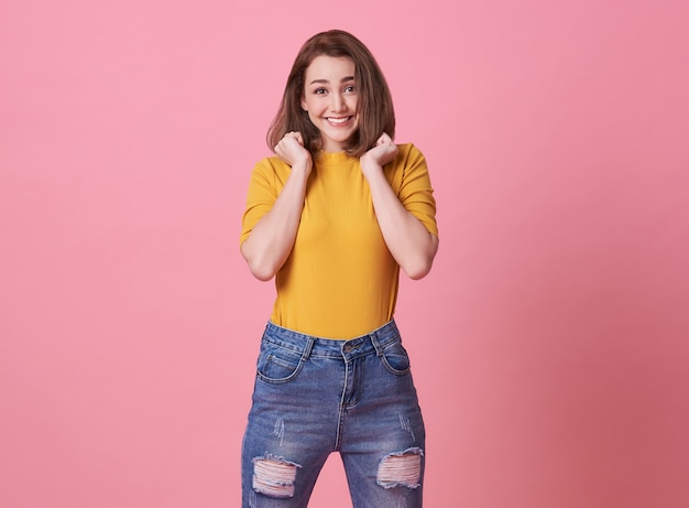 Excited beautiful woman happiness wearing casual yellow t-shirt on pink.