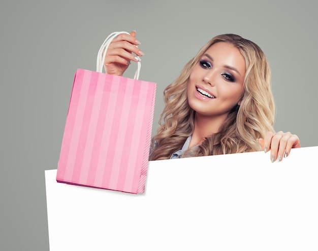 Взволнованная красивая женщина, держащая сумки для покупок и фон белой доски с копировальным пространством для рекламного маркетинга или размещения продукта