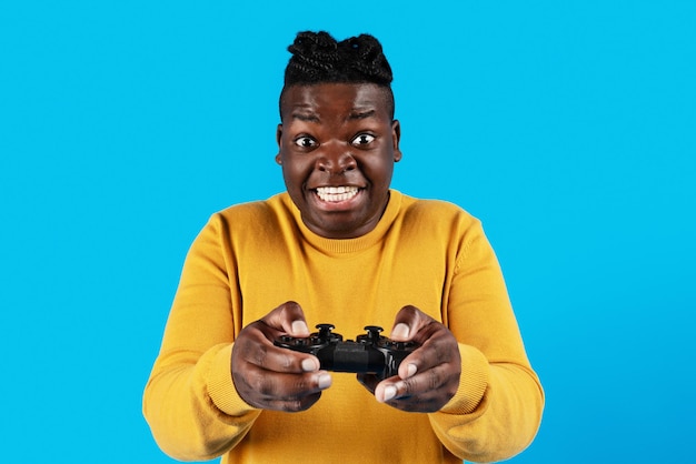 Excited black guy playing video games with joystick over blue background