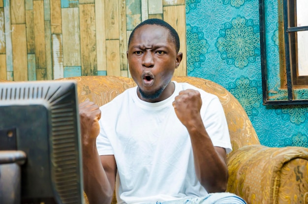 Excited black guy watching sports on tv at home