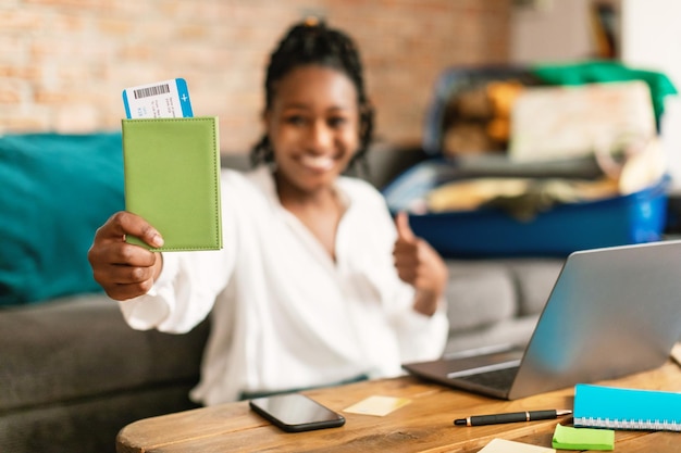 Excited black woman advertising cheap travel tickets offer holding passport and boarding pass