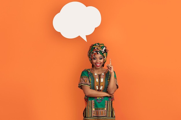 Photo excited black woman in african costume with blank conversation bubble