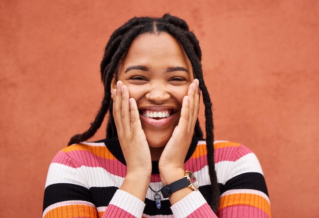 Excited black woman hands and cheeks in portrait by city wall background with smile happiness and beauty Gen z student girl young model and fashion in urban metro for adventure happy and freedom