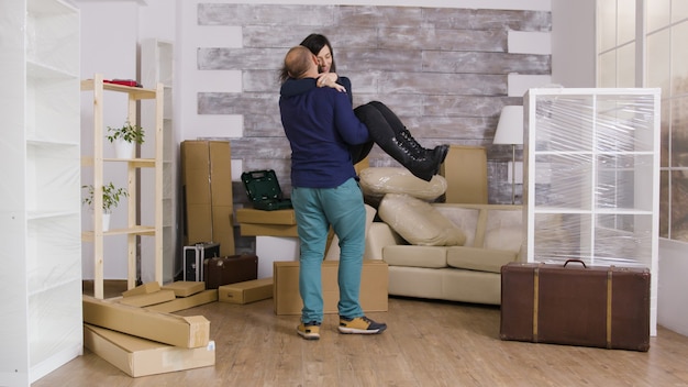 Excited boyfriend spinning his girlfriend in their new apartment. Cheerful young couple.