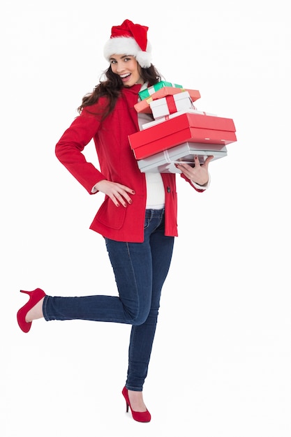 Excited brunette in red coat holding many gifts 