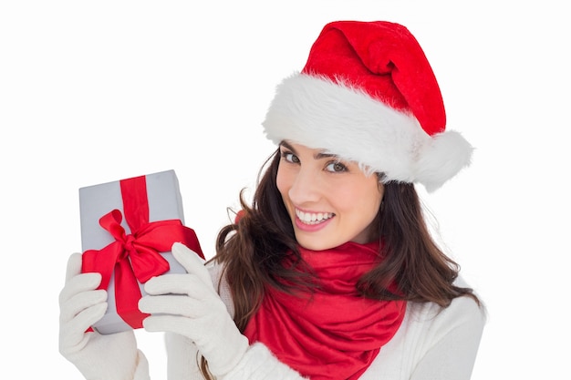 Возбужденная брюнетка в шляпе Санта показывает подарок