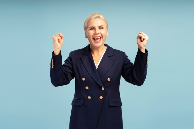 Excited businesswoman celebrating success on blue background