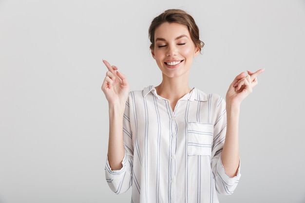 白い背景の上に分離された幸運のために交差した指を保持している興奮した白人女性