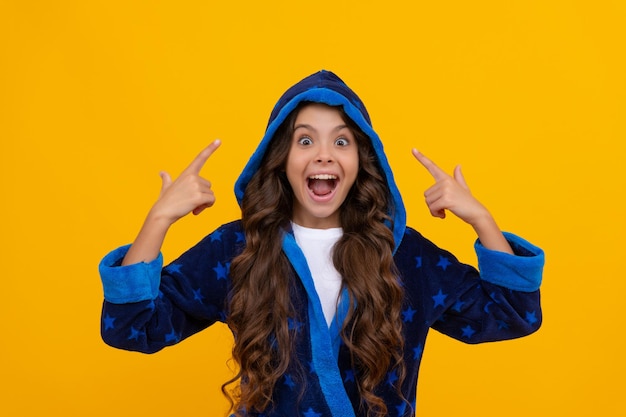 Excited child in hooded bathrobe happy screaming pointing fingers yellow background point