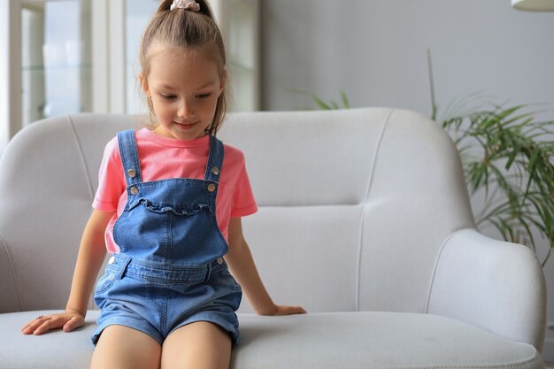 Bambino eccitato che guarda l'obbiettivo mentre è seduto nel soggiorno di casa.